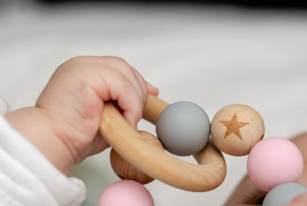 Close up of a baby´s hand, playing with a wooden toy. Unfocused background